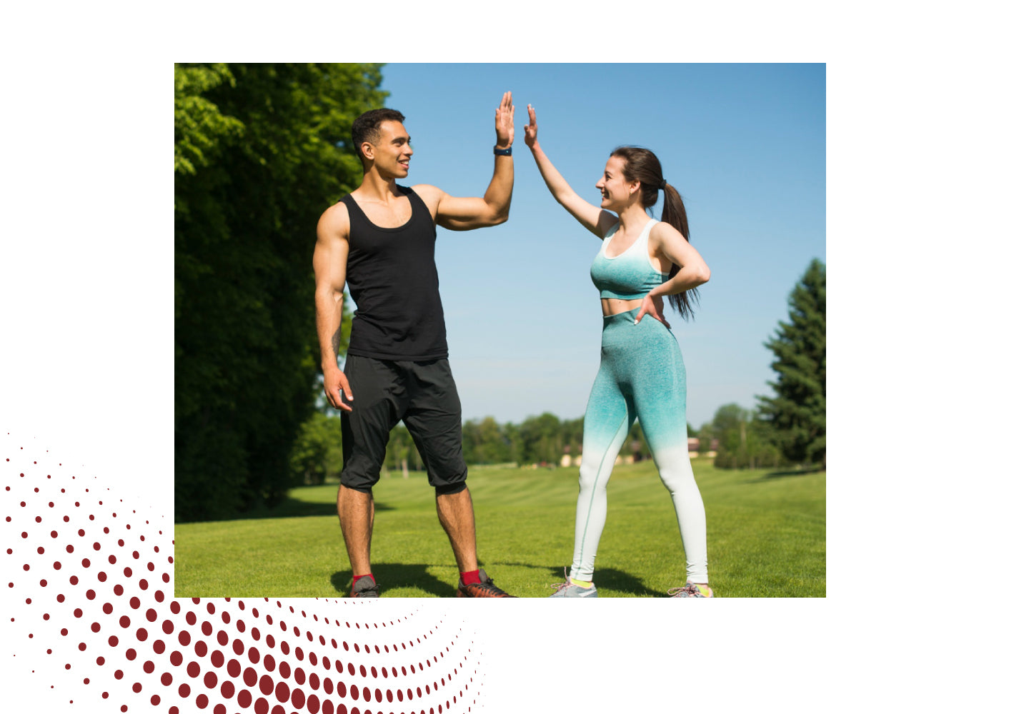 Man and woman in activewear giving a high five outdoors on green grass, symbolizing fitness, motivation & healthy lifestyle.