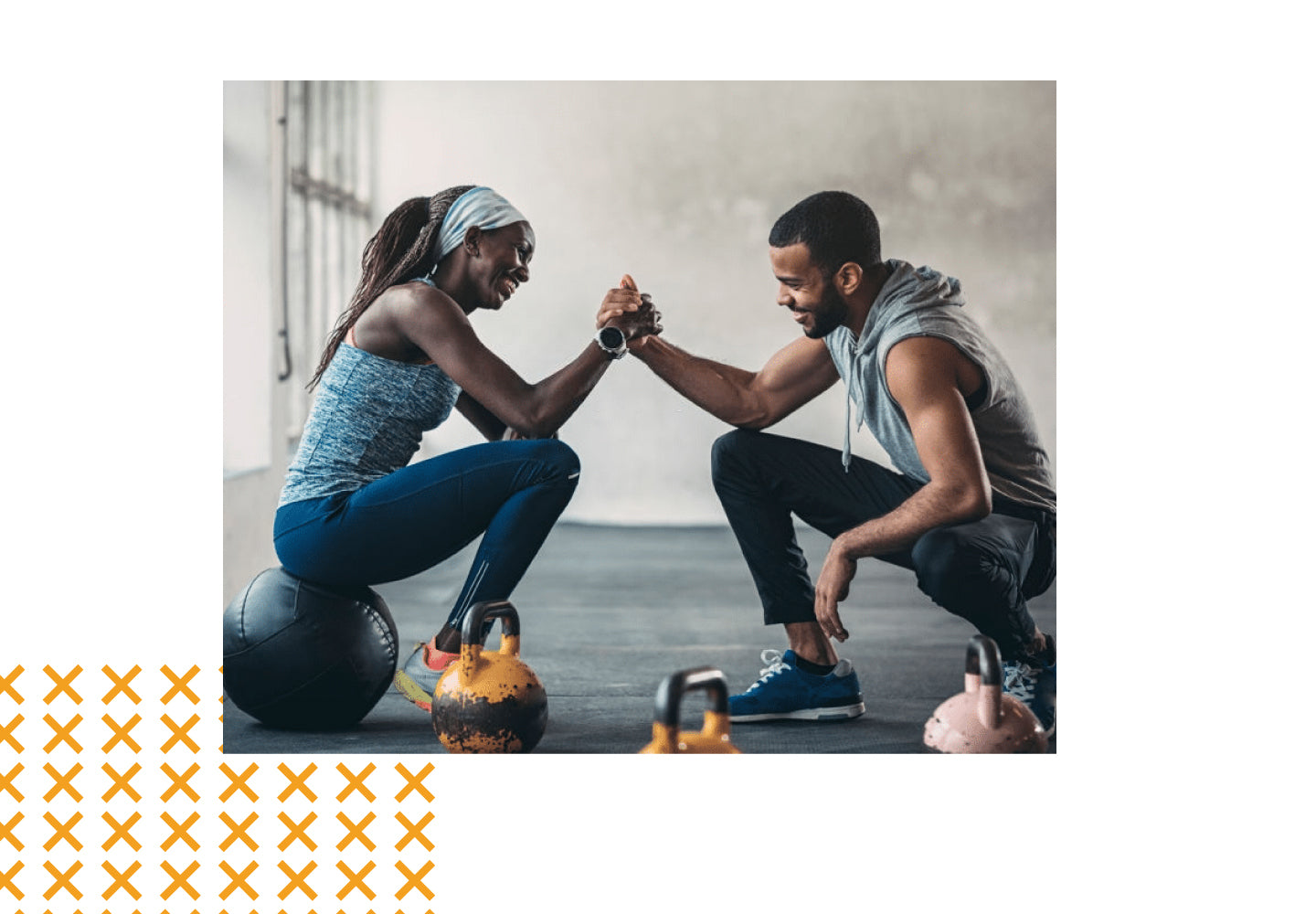 Fit man and woman smiling and arm wrestling in gym with kettlebells, showing strength, energy, and active lifestyle
