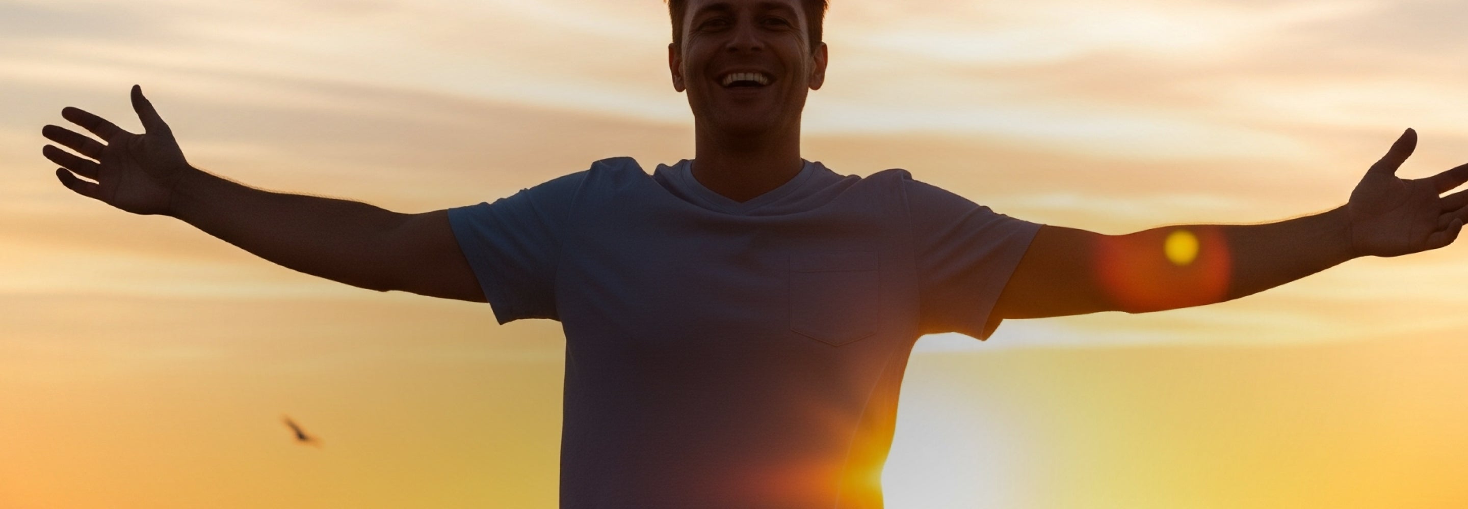 Person with arms outstretched against a sunset sky