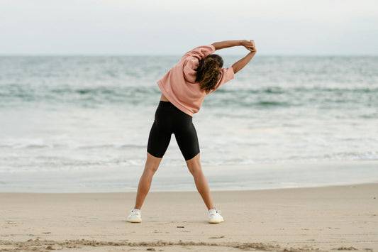 Person stretching on the beach to promote daily movement, stress balance, and healthy lifestyle habits in 2026