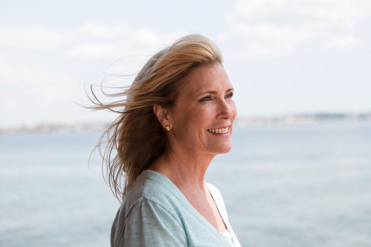 Relaxed middle-aged woman by the seaside enjoying fresh air and calm, supporting overall menopause well-being