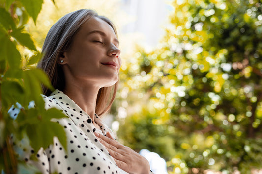 Woman practicing calm, deep breathing in a green natural setting, symbolizing easy breathing and lung comfort supported by mullein leaf.