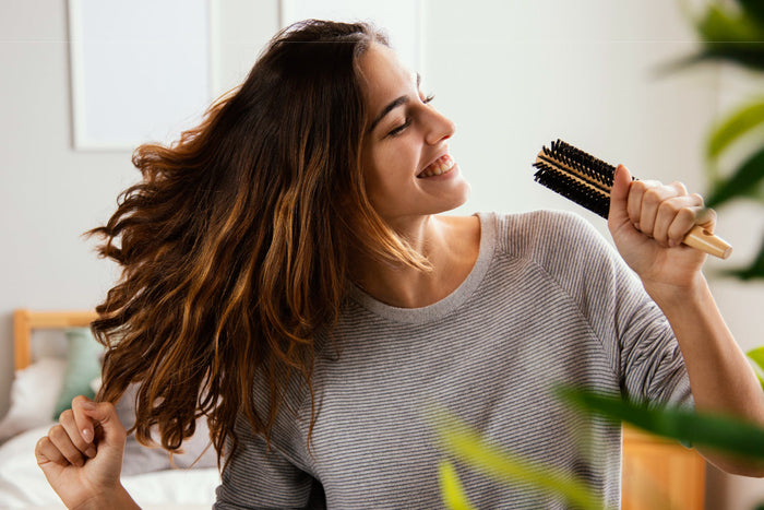 Woman brushing long healthy hair showing strong shiny hair after proper hair nutrition