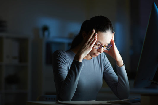Woman experiencing headache and stress while working late at computer, highlighting mental strain, burnout, and nutritional support importance