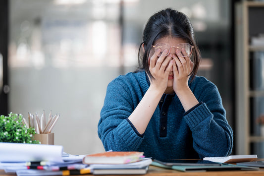 Person sitting at a desk with hands over face, feeling exhausted and overwhelmed, a common sign of unstable blood sugar levels