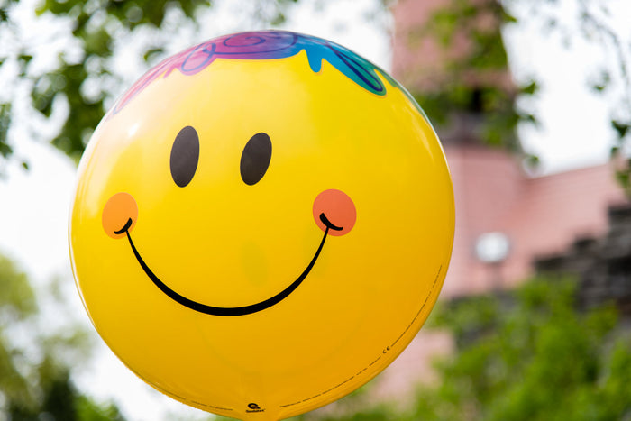 Bright smiley face balloon outdoors symbolizing positivity, emotional balance, and simple daily habits that support mental wellness in 2026.