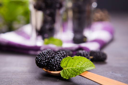 Fresh mulberries with green leaf on a wooden spoon, showcasing antioxidant-rich ingredients linked to post-meal glucose support