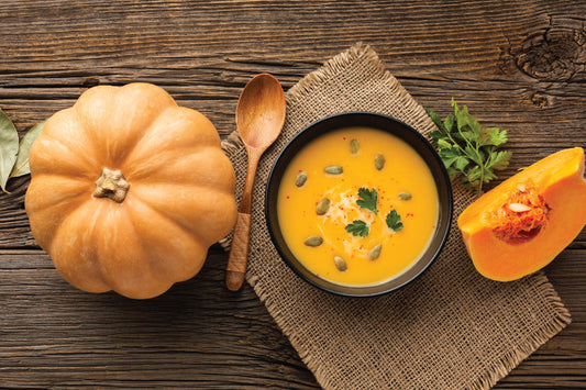Creamy fall pumpkin soup rich in gut-nourishing fiber, served with fresh pumpkin on a rustic wooden table—perfect for boosting immunity during the cozy autumn season.
