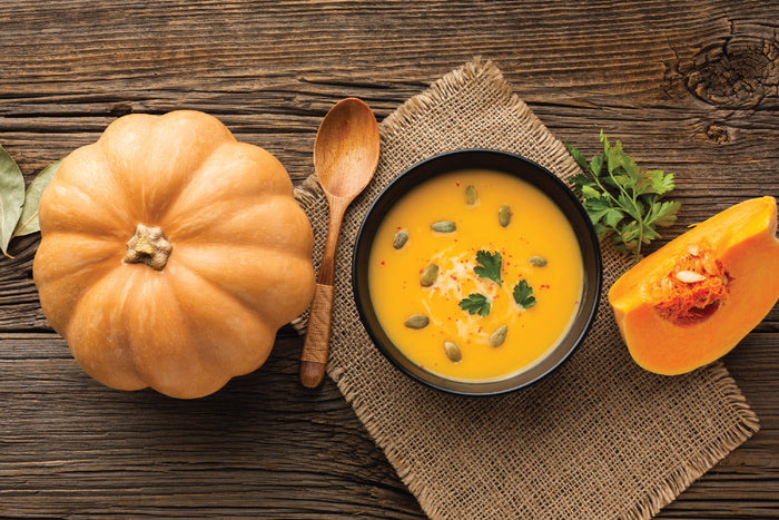 Creamy fall pumpkin soup rich in gut-nourishing fiber, served with fresh pumpkin on a rustic wooden table—perfect for boosting immunity during the cozy autumn season.