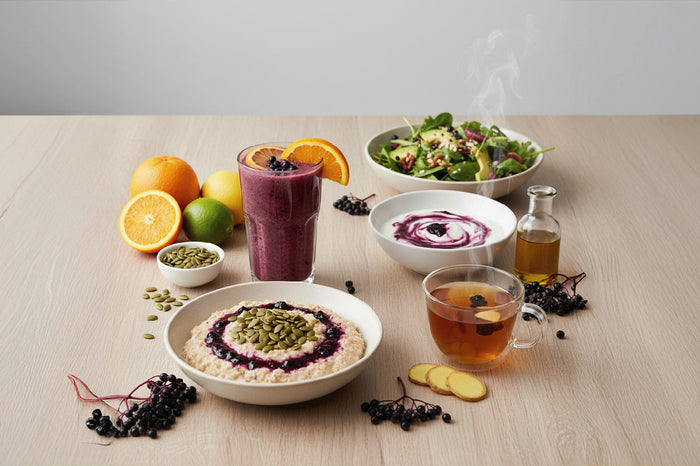 Elderberry smoothie, oatmeal with seeds, yogurt, salad, and tea paired with citrus and ginger for nutritious fall meals.
