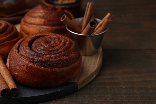 Freshly baked cinnamon rolls with cinnamon sticks representing sweet cravings and comforting cinnamon-flavored foods