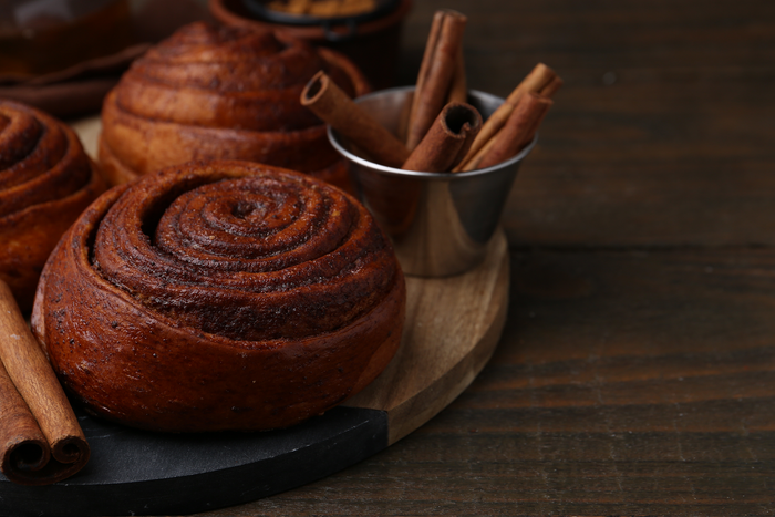 Freshly baked cinnamon rolls with cinnamon sticks representing sweet cravings and comforting cinnamon-flavored foods