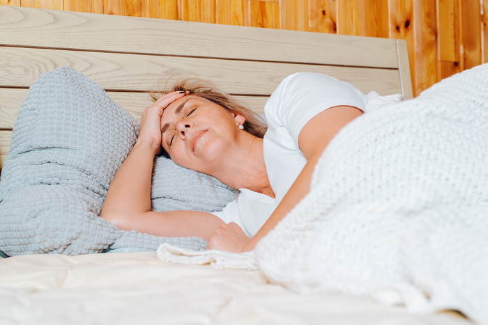 Middle-aged woman resting in bed peacefully, representing improved sleep quality and recovery supported by healthy vitamin D levels