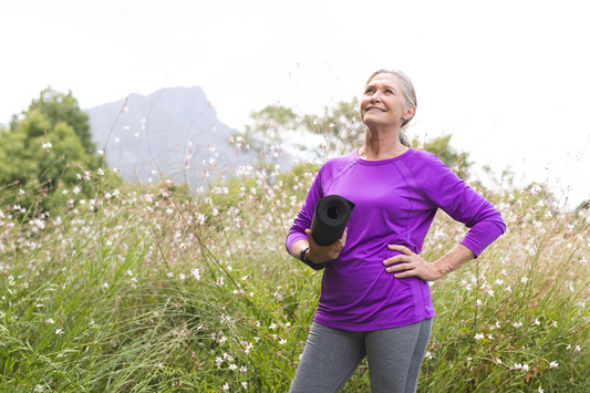 Smiling woman holding a yoga mat outdoors representing balanced energy, recovery, and healthy active aging with magnesium support.