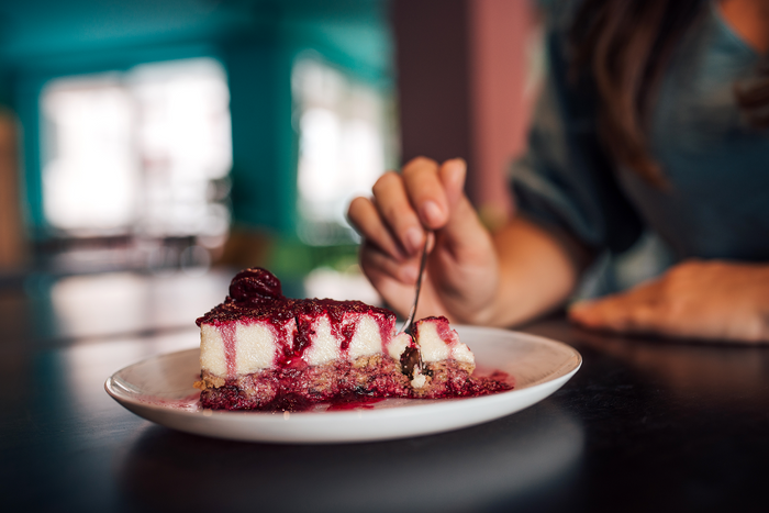 Slice of cheesecake being eaten representing dessert cravings, sugar urges, and post-meal sweet temptations.