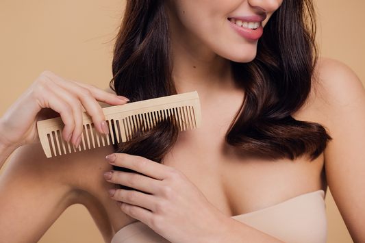Woman gently combing smooth, shiny hair with a wooden comb, highlighting healthy hair care supported by fish collagen and nutrition.