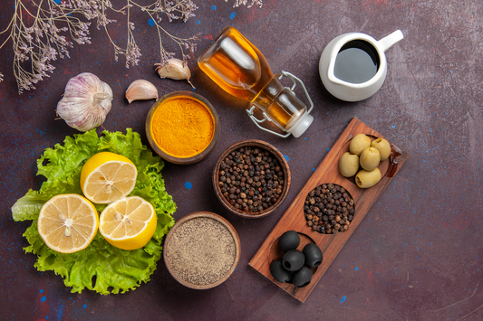 Fresh herbs, lemons, turmeric, garlic, olives, and spices arranged as nutrient-rich ingredients supporting bone wellness naturally.