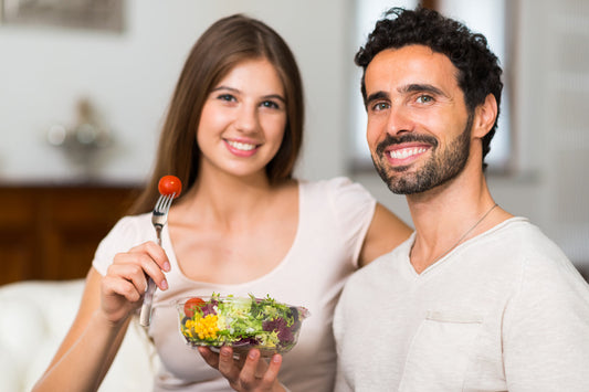 Smiling couple eating fresh vegetable salad on Valentine’s Day to support heart health and balanced glucose levels