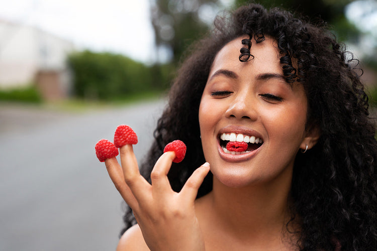 Woman enjoying fresh raspberries, symbolizing natural fruit-based wellness and immune support.