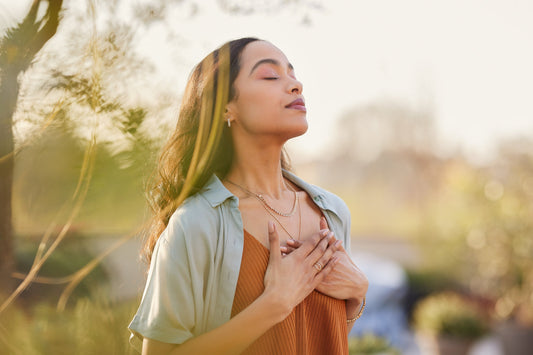 Woman practicing deep breathing outdoors to support respiratory health and overall well-being