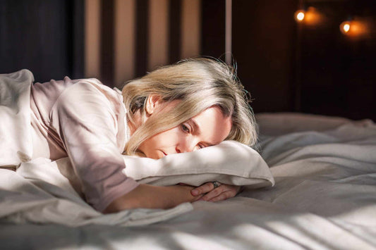 Woman resting on a pillow at night with a tired expression, highlighting menopause-related insomnia and difficulty falling asleep naturally