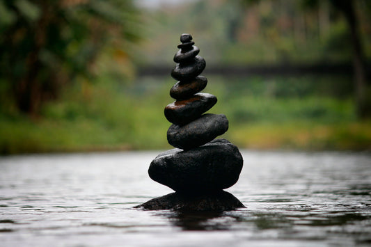 Stack of balanced stones in calm water symbolizing relaxation, balance, and inner peace.