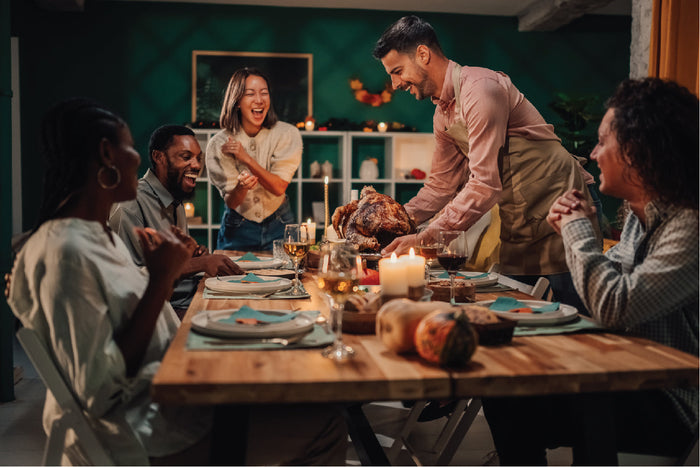 Thanksgiving dinner celebration with friends and roasted turkey on the table.