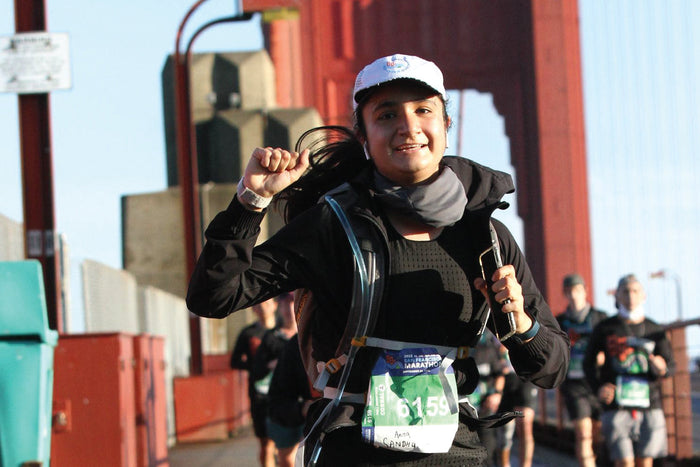 Anna Sandhu running across the Golden Gate Bridge during a marathon, highlighting the importance of hydration for endurance and strength.