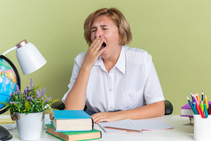 Woman yawning at her desk, illustrating feelings of sluggishness and fatigue that can occur after meals.