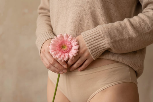 Woman holding a pink flower near her lower abdomen, symbolizing feminine wellness, vaginal health, and the importance of maintaining a balanced vaginal microbiome.