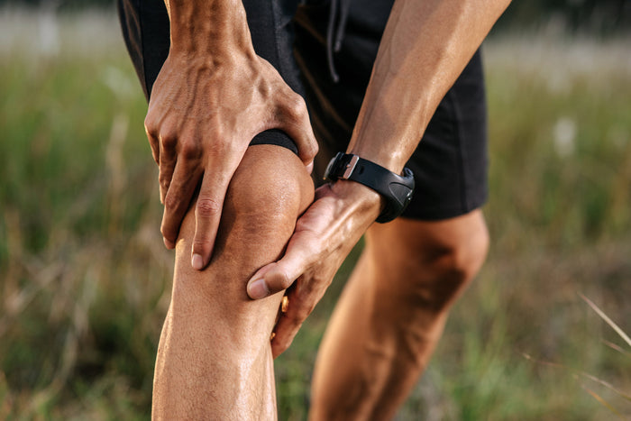 Athlete holding a painful knee outdoors, highlighting how low vitamin D may contribute to muscle weakness and knee discomfort.