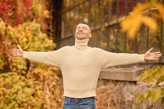 Man taking a deep breath outdoors in fresh autumn air with open arms for better seasonal breathing
