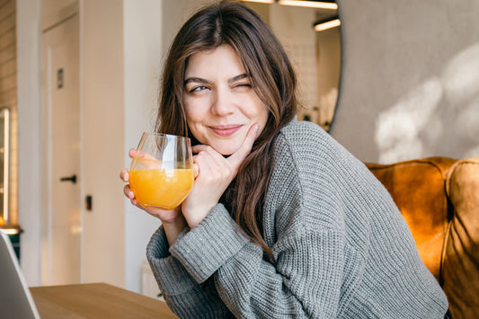 Woman enjoying a refreshing citrus herbal drink indoors for seasonal wellness and respiratory comfort during high pollen days.