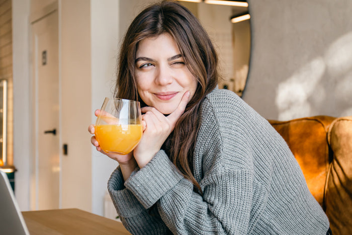 Woman enjoying a refreshing citrus herbal drink indoors for seasonal wellness and respiratory comfort during high pollen days.