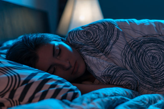 Woman sleeping peacefully in bed at night, showing deep restorative sleep supported by healthy bedtime habits and consistent routines