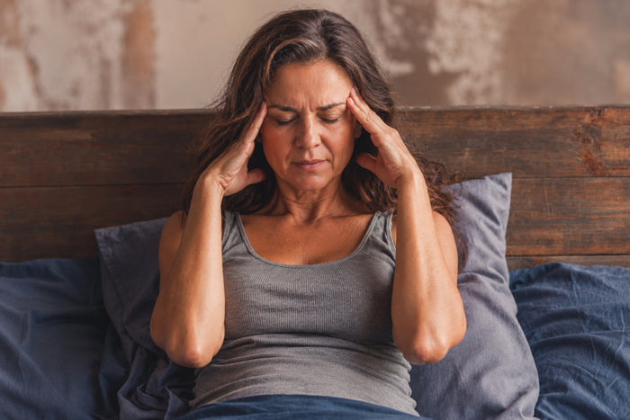 Middle-aged woman sitting in bed with stress and sleeplessness linked to menopause symptoms during summer nights