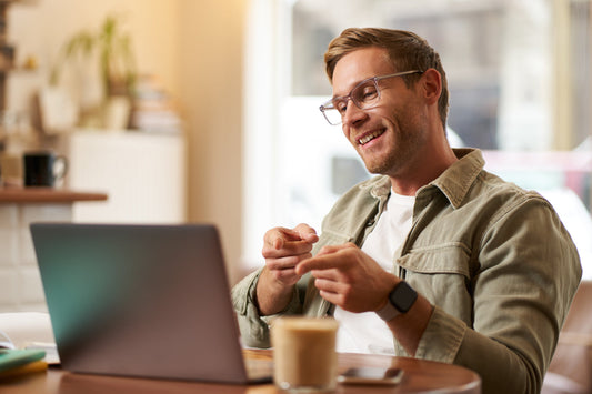 Man smiling while working on laptop at home, representing improved focus, wellness, and balanced daily recovery routines.