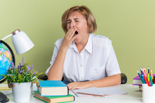 Woman yawning at her desk, illustrating feelings of sluggishness and fatigue that can occur after meals.