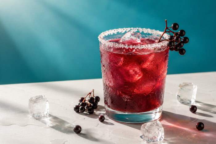 Chilled elderberry mocktail with ice and fresh elderberries, offering a refreshing antioxidant-rich summer drink for hydration and everyday wellness.