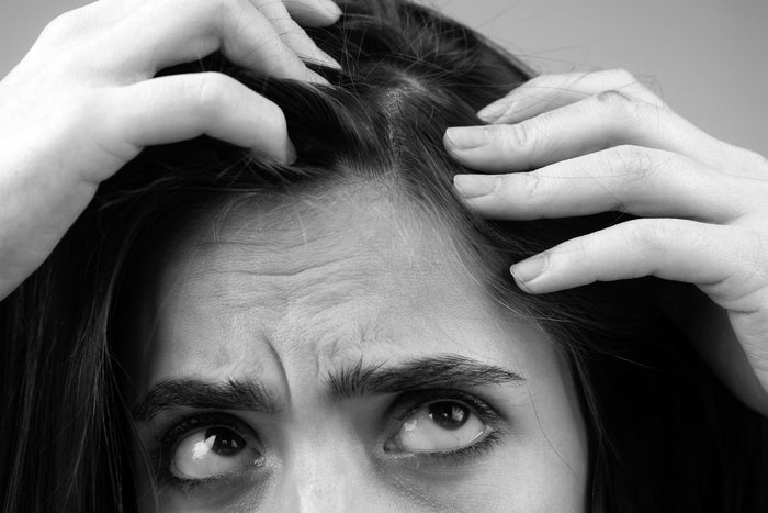 Close-up of a person examining thinning hair and scalp, illustrating age-related hair follicle shrinkage and hair thinning.