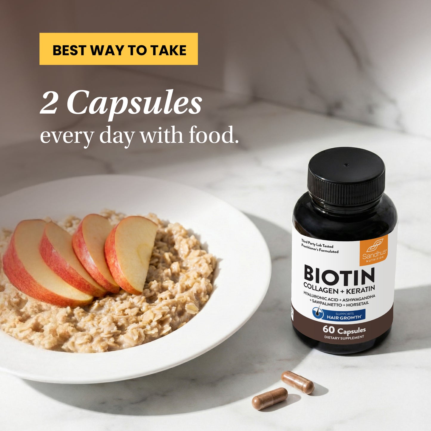 Biotin supplement bottle with capsules and a bowl of oatmeal with apples on a marble surface.