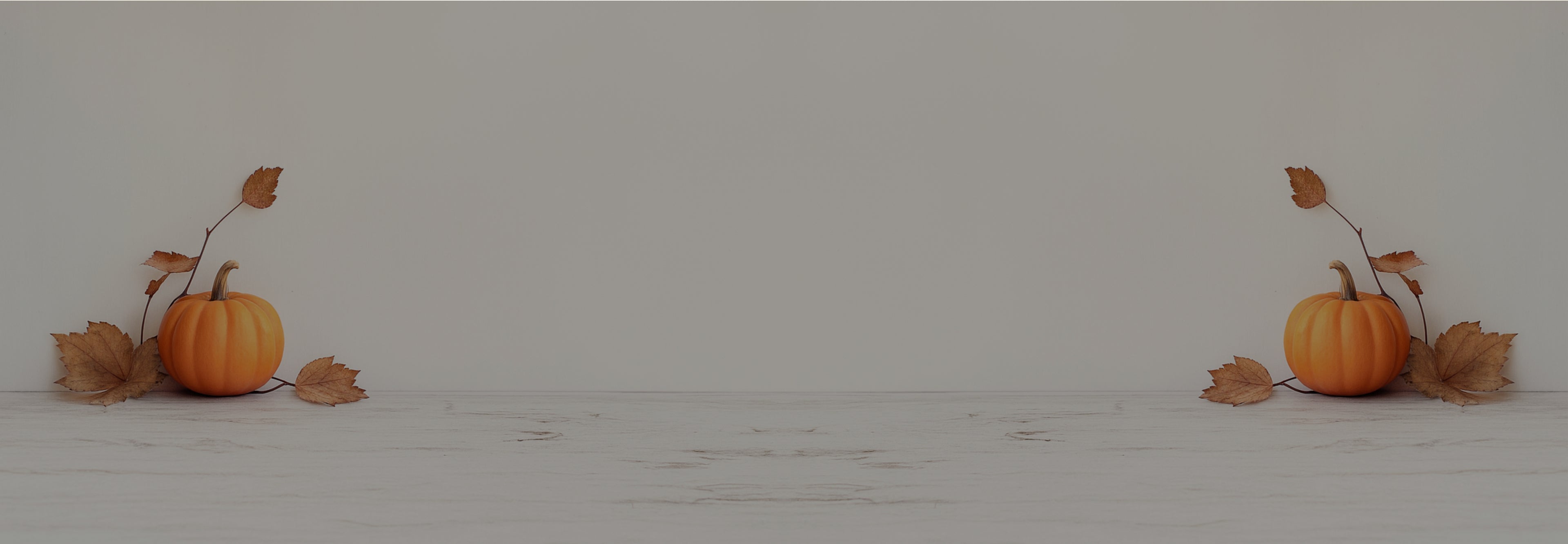 Two small pumpkins with leaves on a light gray background