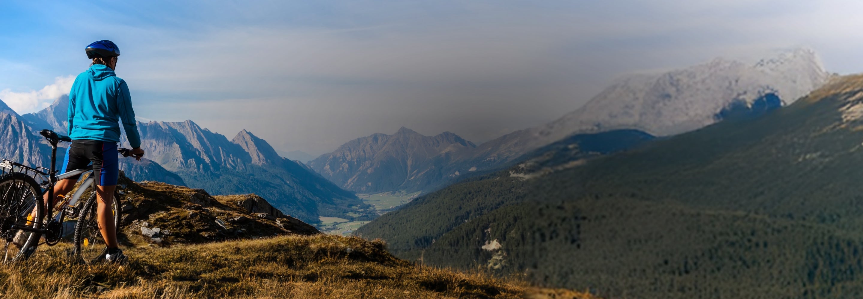 Person with a bicycle overlooking a mountain landscape