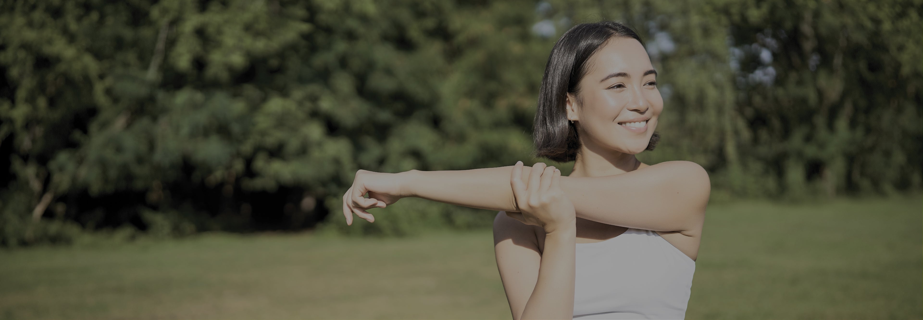 Woman stretching outdoors with greenery in the background