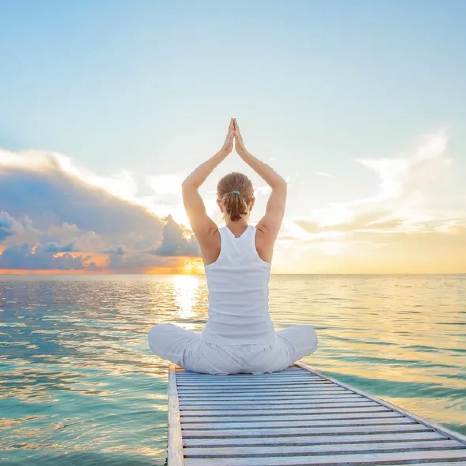 Woman practicing yoga at sunrise on ocean deck, symbolizing peace.
